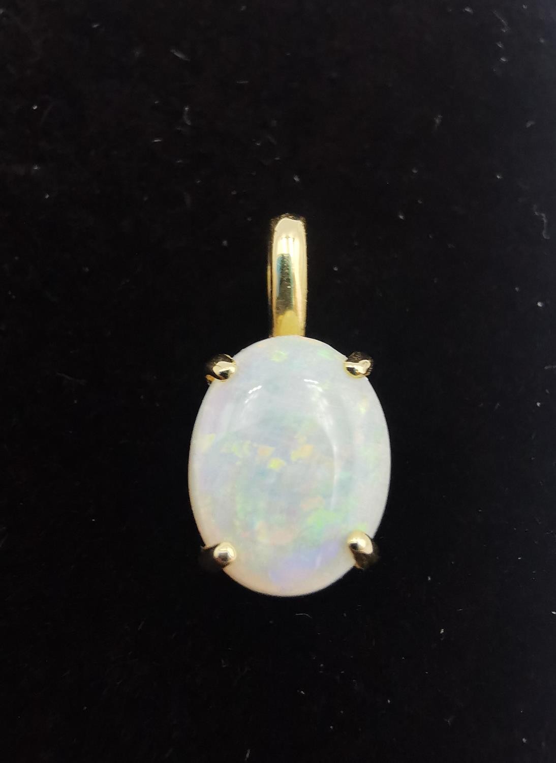 An 18ct yellow gold mounted opal pendant. The pendant set with an oval opal cabochon in an open back