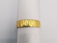 A vintage 22ct yellow gold band by Slade & Woolf Ltd. A flat band with an engraved bark texture.
