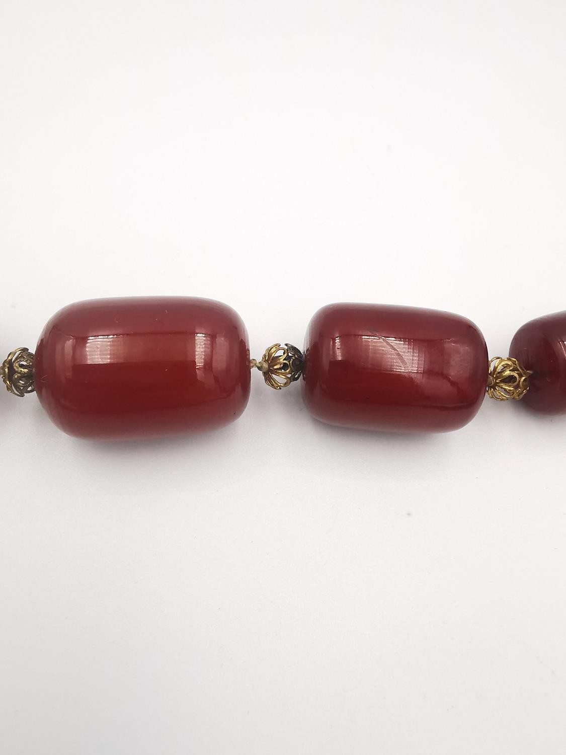 An early 20th century long cherry amber Bakelite graduated bead necklace. In between each Bakelite - Image 3 of 4