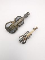 Two early 20th century white metal (tests as silver) violin brooches, one set with panels of