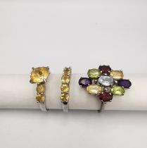 Three gem set silver rings, a Citrine flanked solitaire and matching five stone ring and a garnet,