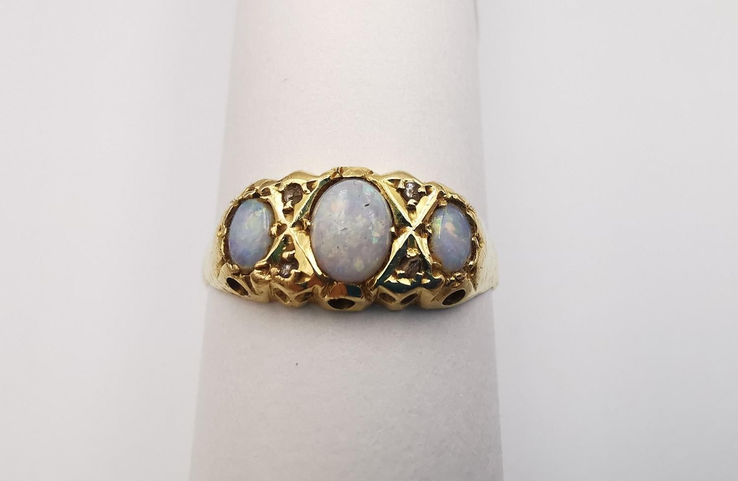 A Victorian 18ct yellow gold three stone opal and diamond ring. Set with three oval opal cabochons
