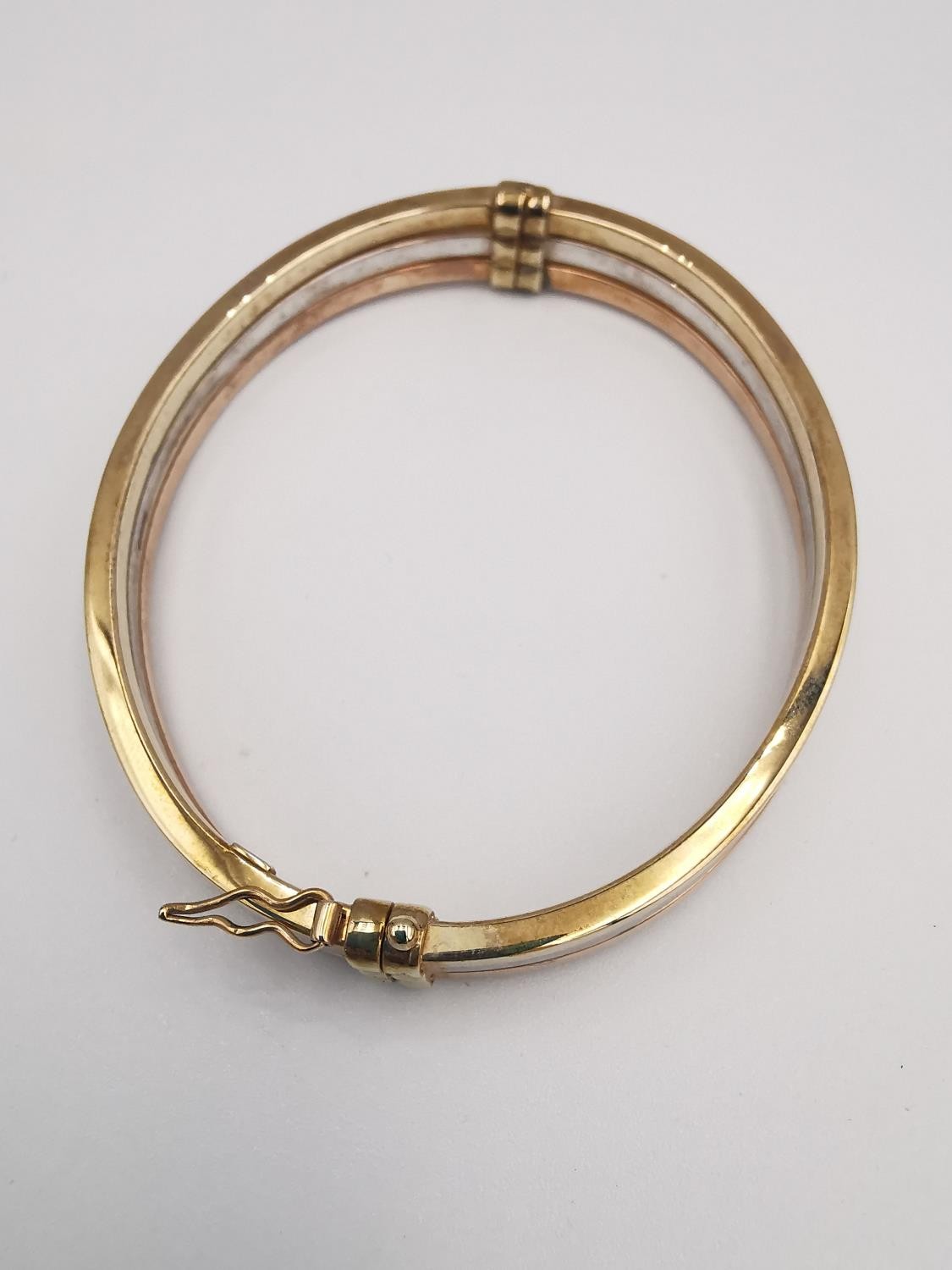 A modern 9ct three colour gold hinged bangle. The bangle comprised of three bands, white, rose and - Image 3 of 5