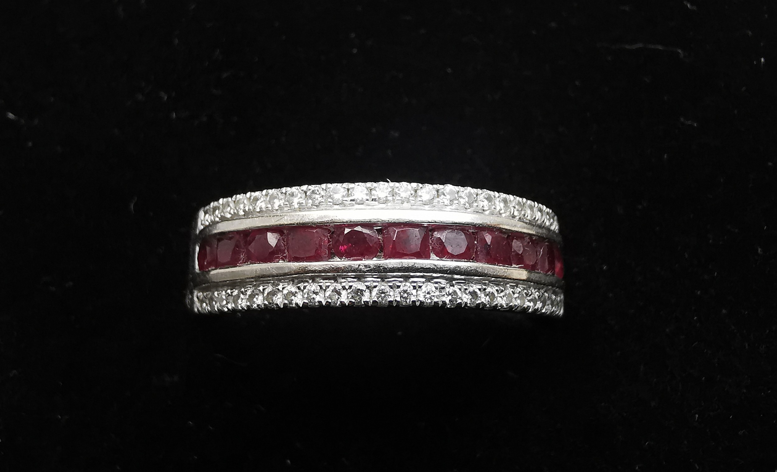 An 18ct white gold ruby and diamond half eternity ring, set with a channel of eleven oval mixed - Image 2 of 4