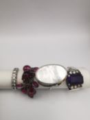 Four silver and white metal gem set rings, a mother of pearl statement ring, an amethyst cocktail