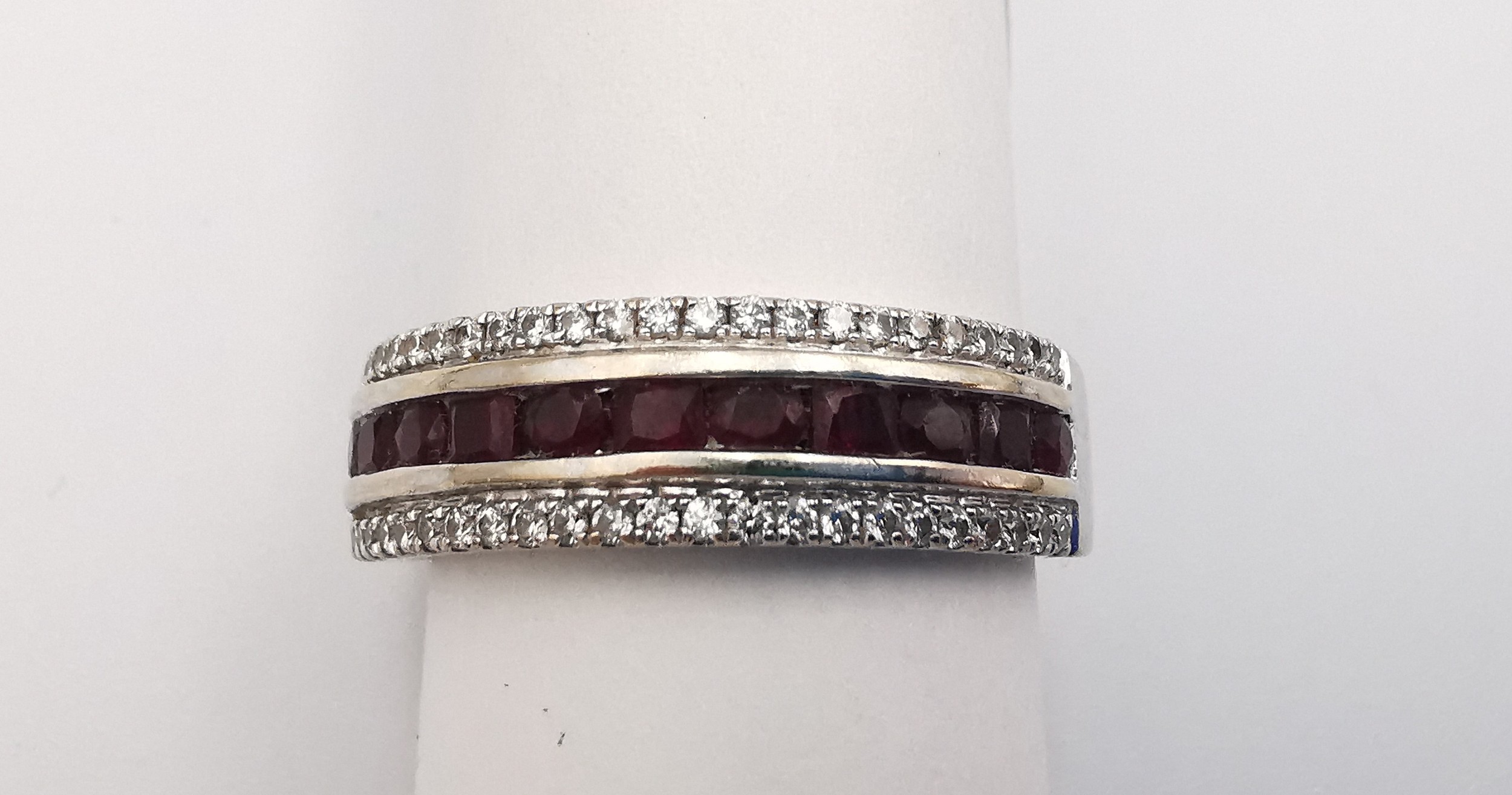 An 18ct white gold ruby and diamond half eternity ring, set with a channel of eleven oval mixed - Image 4 of 4