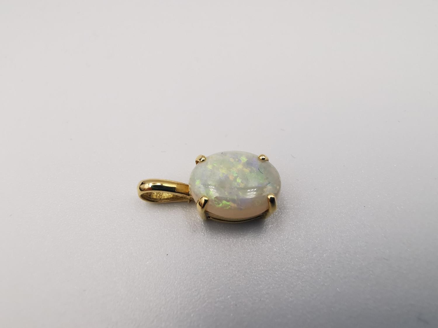 An 18ct yellow gold mounted opal pendant. The pendant set with an oval opal cabochon in an open back - Image 4 of 8