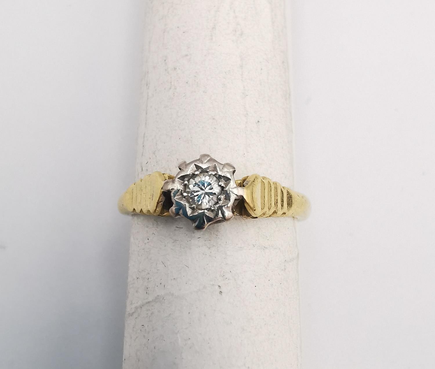 An 18ct yellow and white gold diamond solitaire ring. Set to centre with a round brilliant cut