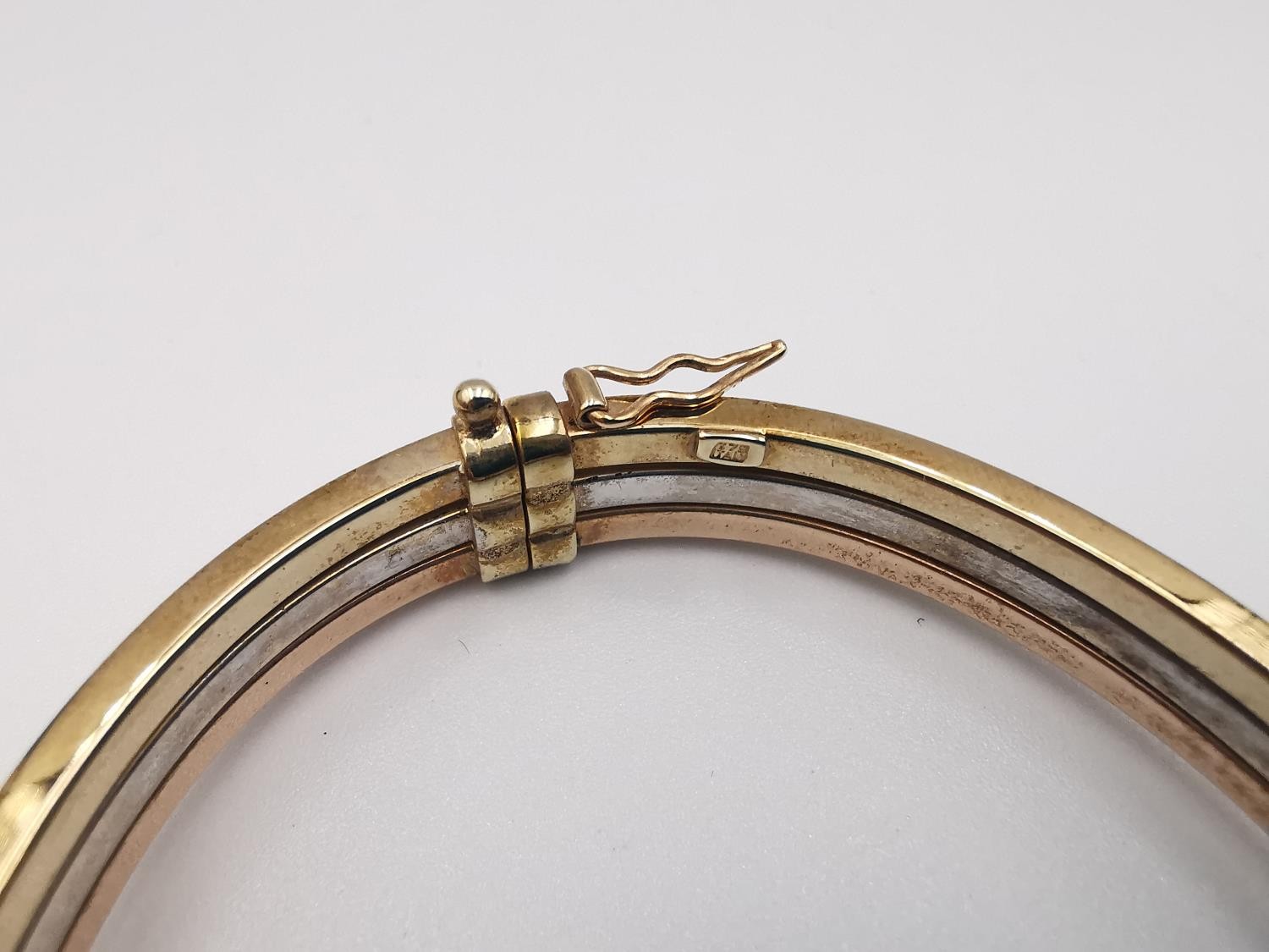 A modern 9ct three colour gold hinged bangle. The bangle comprised of three bands, white, rose and - Image 5 of 5