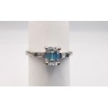 An Art Deco style 18ct white gold modern emerald cut diamond flanked solitaire ring. Set to centre