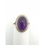A 9ct yellow gold amethyst dress ring, set with an oval amethyst cabochon with an approximate