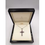 A boxed 9ct white gold ruby and diamond cross and chain. The cross set with twelve square channel