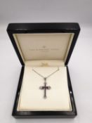 A boxed 9ct white gold ruby and diamond cross and chain. The cross set with twelve square channel