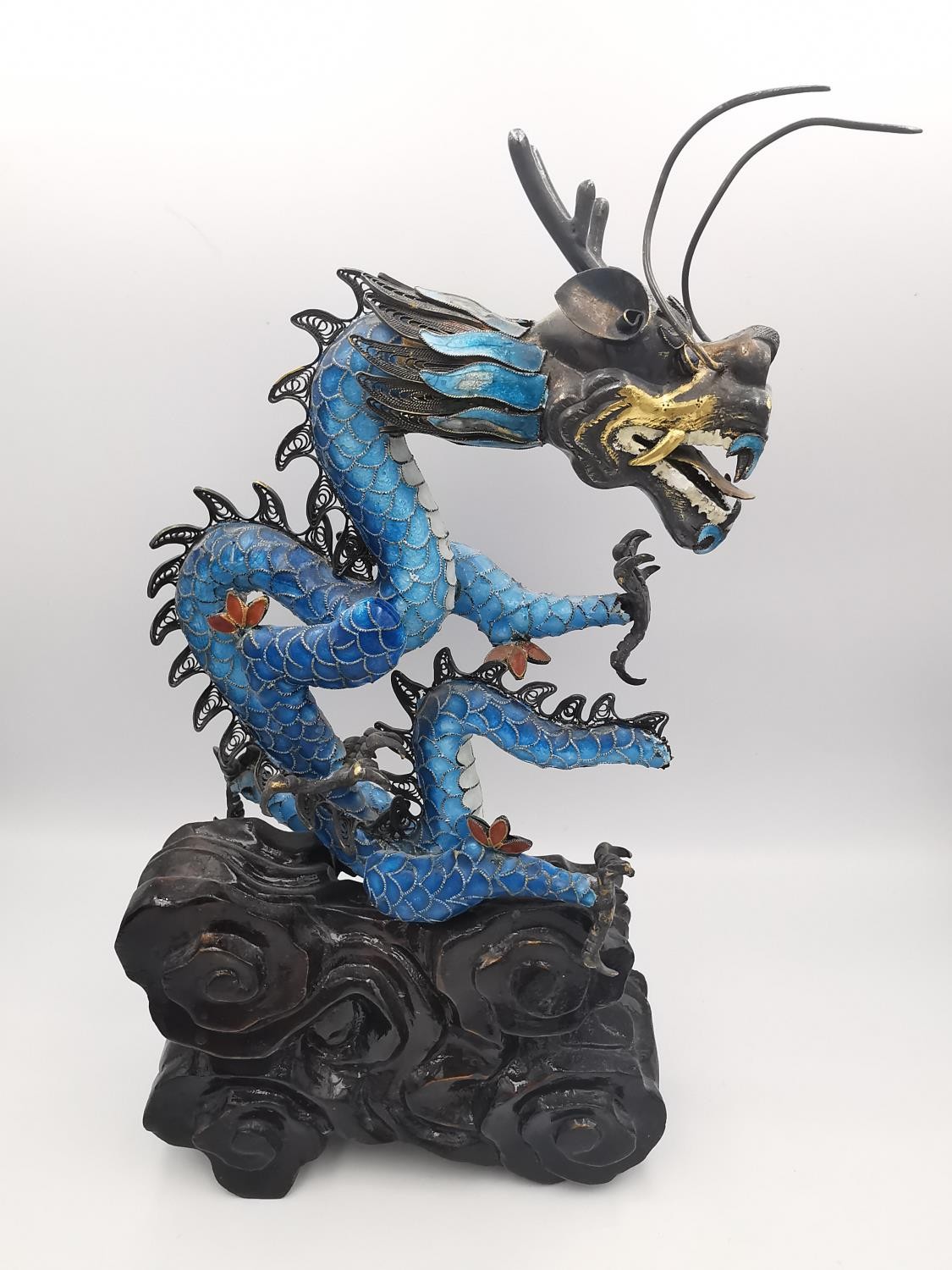 An early 20th century Chinese white metal and cloisonne enamel wirework dragon on a carved cloud