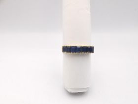A yellow metal sapphire seven stone ring, set with seven rectangular mixed cut sapphires with a