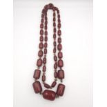 An early 20th century long cherry amber Bakelite graduated bead necklace. In between each Bakelite