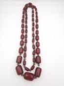 An early 20th century long cherry amber Bakelite graduated bead necklace. In between each Bakelite