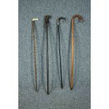 Four walking sticks including two sword sticks. One stick with a carved dogs head and another with a