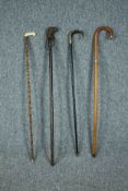 Four walking sticks including two sword sticks. One stick with a carved dogs head and another with a