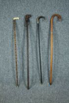 Four walking sticks including two sword sticks. One stick with a carved dogs head and another with a