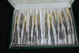 A box of cutlery. Knifes and forks with aluminium handles and gilt decorated finish. Twelve items in