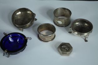 A collection of silver and white metal, including two silver salts, two silver napkin rings, a white