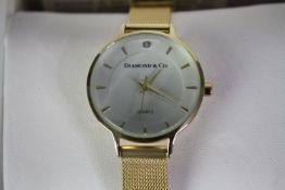 A boxed Diamond and Co ladies quartz watch with gold tone mesh strap and white dial. Box and papers.