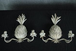 A pair of distressed painted metal twin sconce wall candelabras with pineapple and flowerhead