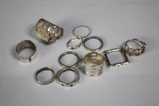 A collection of eleven contemporary silver rings, each with a different design and size. All stamped