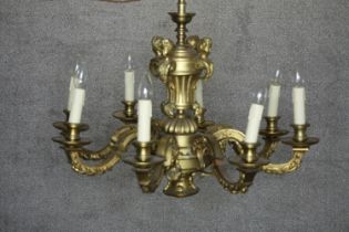 A French brass eight branch chandelier. Mounted with metal cherubs finished in gilt at the base