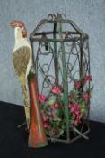 A decorative birdcage with a carved parrot perched outside. The cage containing flowers. H.60 cm.
