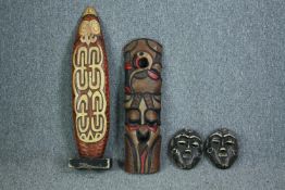 A pair of carved masks, and a decorative panel on stand. H.89cm. (largest)