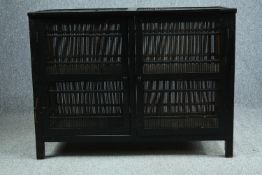 An Eastern lacquered and ebonised cabinet with slatted bamboo sides and doors. H.80 W.108 D.47cm.