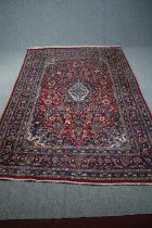 Carpet, a Persian Mashad with central medallion and scrolling flowerhead motifs on a burgundy