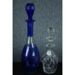 Two decanters. Blue glass with an etched floral pattern. The other, smaller and clear glass H.