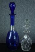 Two decanters. Blue glass with an etched floral pattern. The other, smaller and clear glass H.