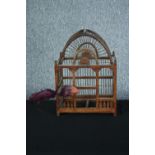 A decorative wooden birdcage with metal bars and a feathered bird. H.42 W.31 D.21 cm.