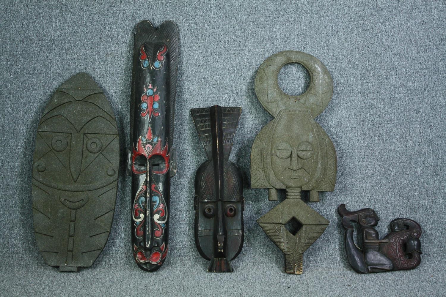 A miscellaneous collection of four carved Eastern and Tribal masks and a carved figure. H.100cm. (