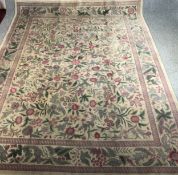 A hand woven carpet with Arts and Crafts flowerhead motifs on a biscuit field within complementary