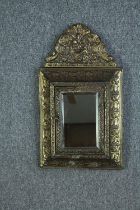 A vintage Dutch repousse brass wall mirror with concealed brush compartment. H.55 W.31 cm.