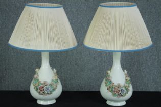 A matching pair of porcelain table lamps decorated with a garland of flowers. H.44 cm. (each)