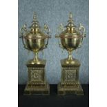 A pair of early 20th century brass and copper classical design twin handled urns on weighted