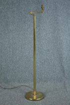 A brass floor standing lamp with adjustable arm. Early to mid twentieth century. H.128 cm.