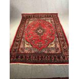 A Persian Sarouk carpet with central medallion and flowerhead motifs across the burgundy field