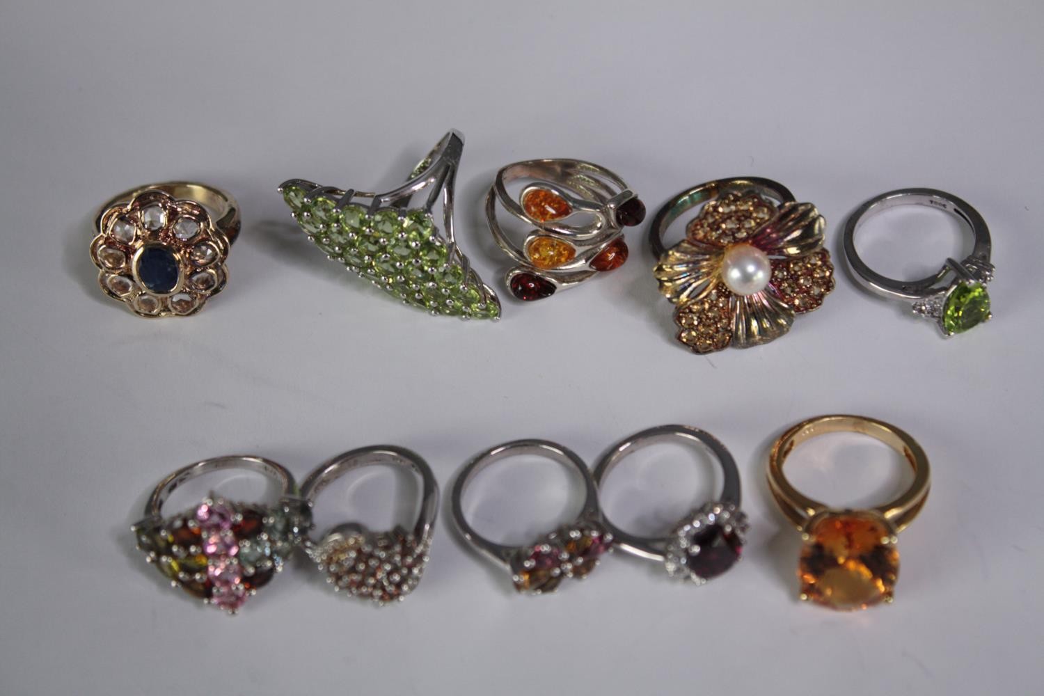 A collection of ten silver gem-set rings of various designs. Set with peridot, Tourmaline,