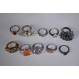 A collection of ten silver gem-set rings of various designs. Set with blue topaz, amethyst and ruby.
