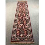 A hand woven runner with a William Morris flowerhead pattern on a burgundy field within