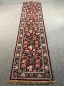 A hand woven runner with a William Morris flowerhead pattern on a burgundy field within