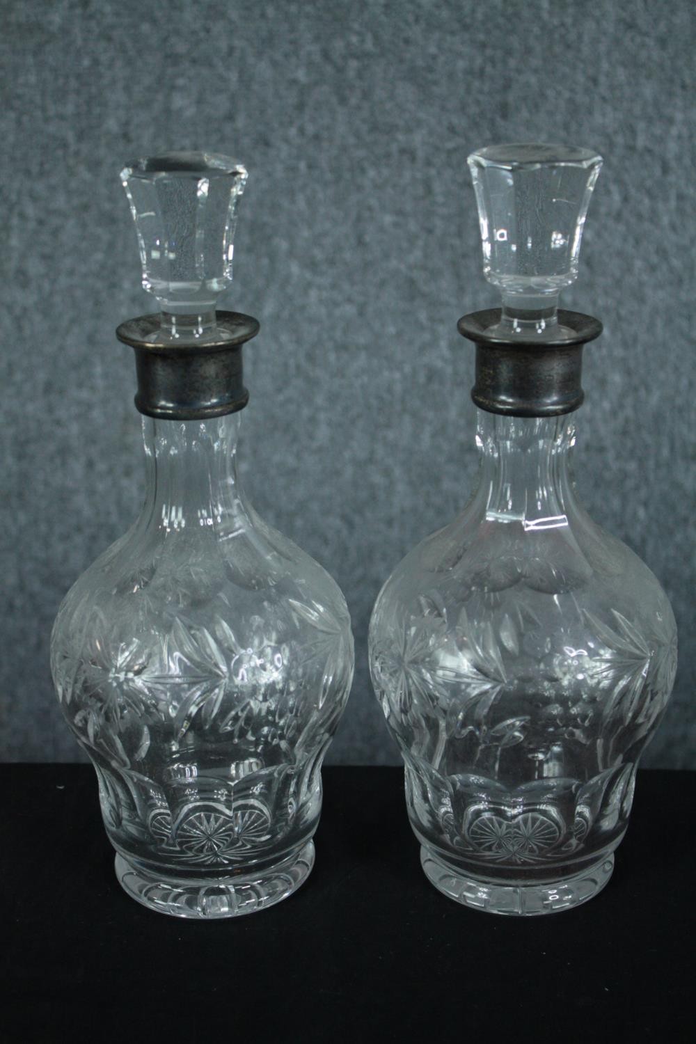 A pair of cut crystal decanters with vine decoration and fitted with silver collars. Hallmarked: