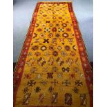 A hand woven Eastern runner with stylised motifs across the ochre field within a deep terracotta